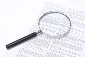 Image of an intricate legal document and a magnifying glass, representing the use of legalese, which is on the decline in popularity.